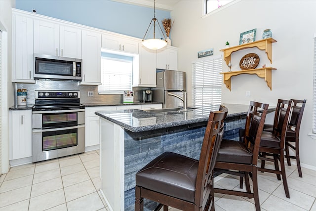 kitchen featuring decorative backsplash, white cabinetry, hanging light fixtures, and appliances with stainless steel finishes