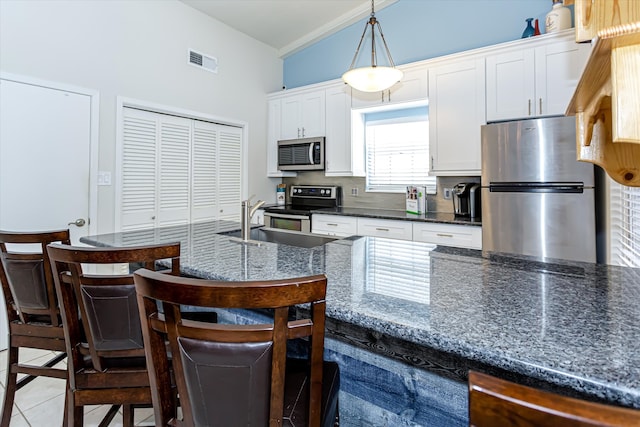 kitchen featuring a breakfast bar, stainless steel appliances, sink, white cabinetry, and hanging light fixtures