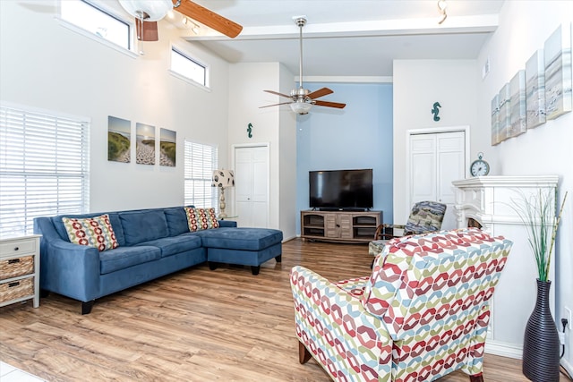 living room featuring hardwood / wood-style flooring, beamed ceiling, and a high ceiling