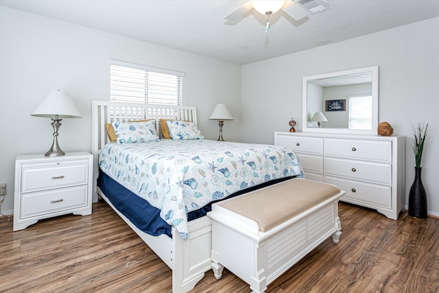 bedroom featuring ceiling fan, dark hardwood / wood-style flooring, and multiple windows