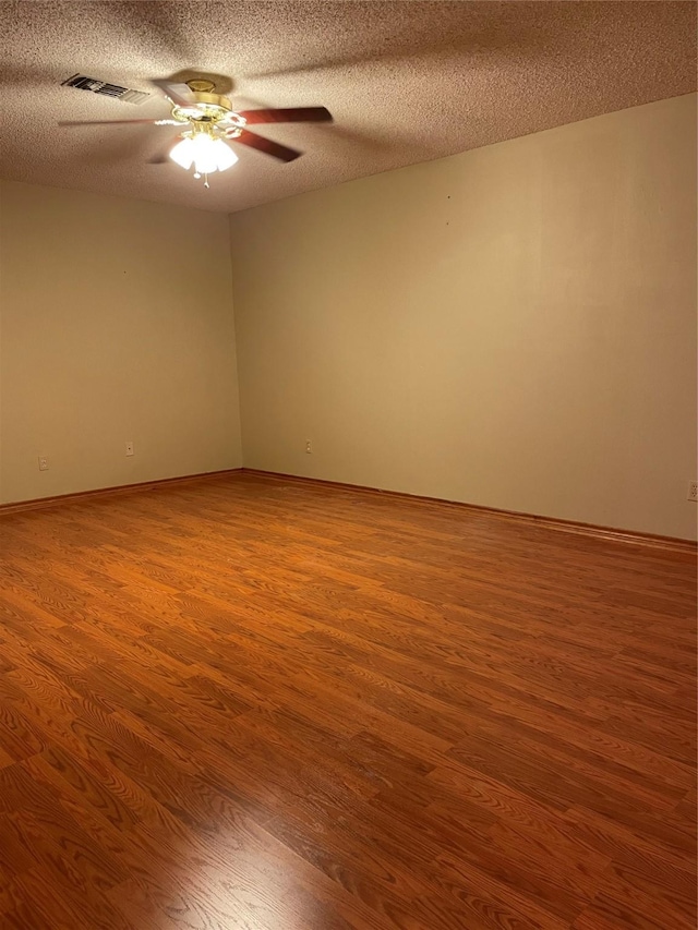 spare room with visible vents, a ceiling fan, wood finished floors, and a textured ceiling