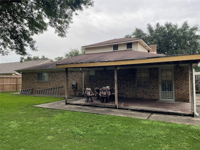 rear view of house with brick siding, fence, and a lawn