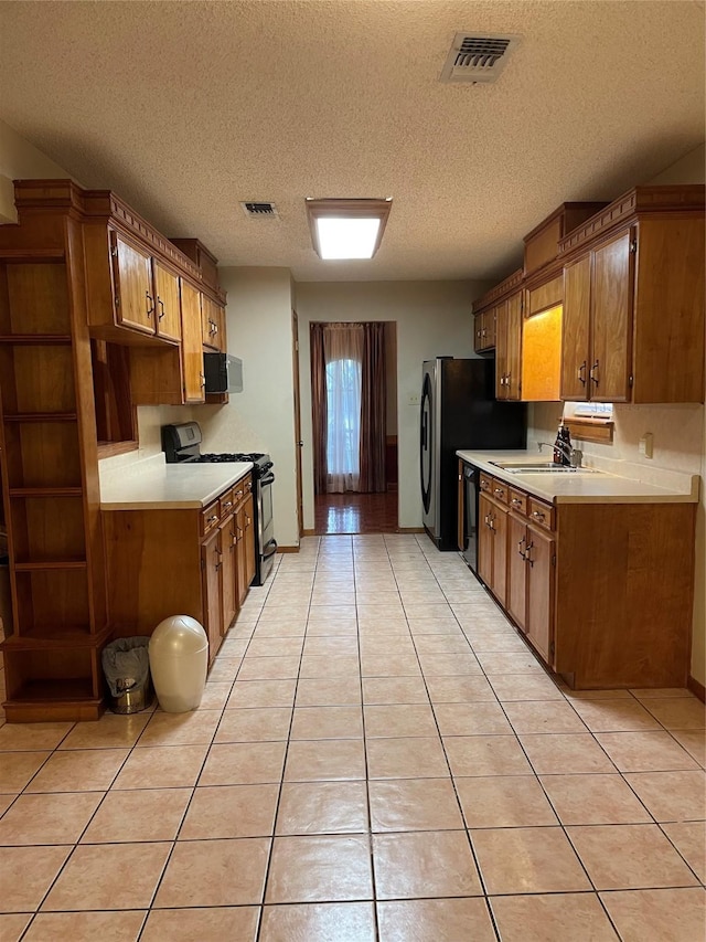 kitchen featuring a textured ceiling, visible vents, appliances with stainless steel finishes, light tile patterned flooring, and light countertops