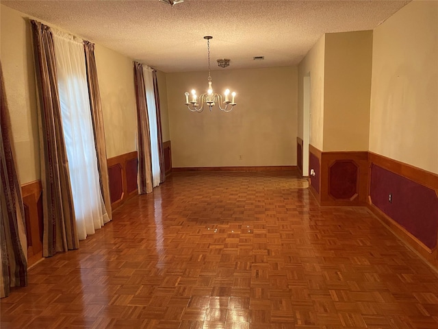 interior space featuring visible vents, a wainscoted wall, an inviting chandelier, and a textured ceiling