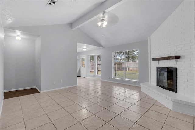 unfurnished living room with a textured ceiling, ceiling fan, light tile patterned floors, lofted ceiling with beams, and a fireplace