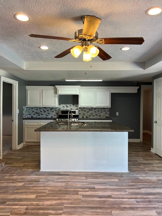 712 S Blackwell St, La Porte, TX 77571 - kitchen featuring a textured ceiling, a sink, baseboards, tasteful backsplash, and white cabinetry