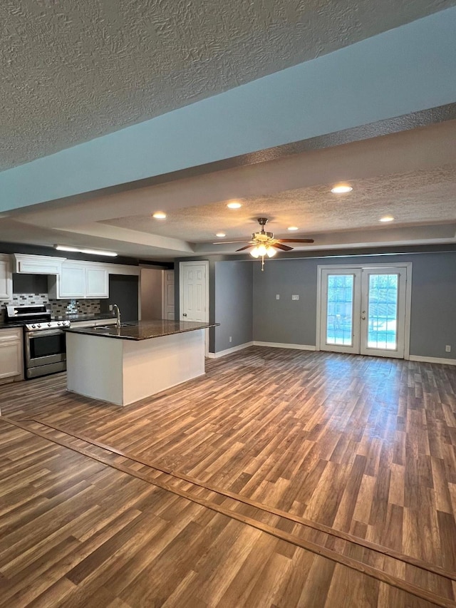 712 S Blackwell St, La Porte, TX 77571 - kitchen with stainless steel gas stove, open floor plan, dark wood-style flooring, dark countertops, and a textured ceiling