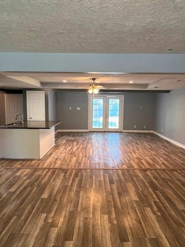 712 S Blackwell St, La Porte, TX 77571 - unfurnished living room with dark wood-style floors, baseboards, a sink, a textured ceiling, and recessed lighting