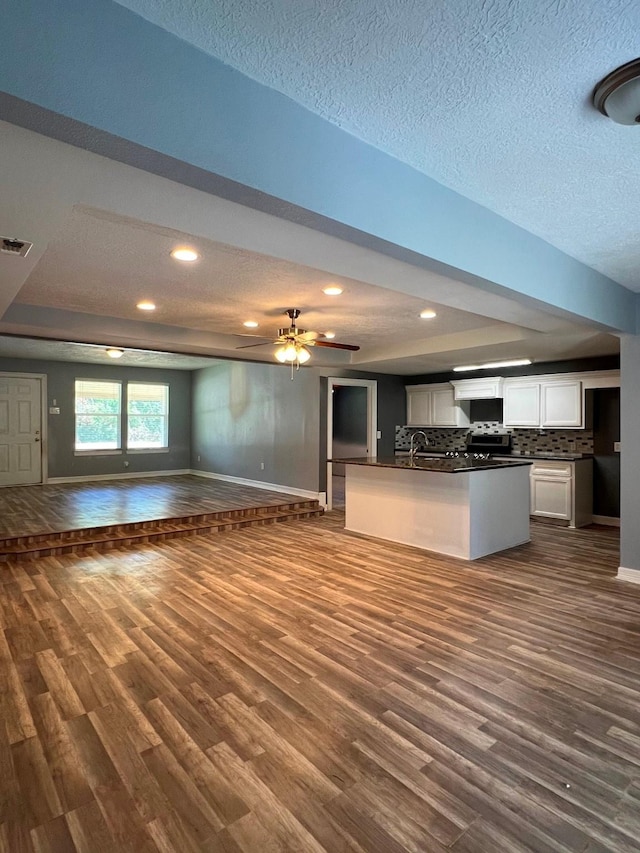 712 S Blackwell St, La Porte, TX 77571 - kitchen with open floor plan, dark countertops, dark wood-type flooring, white cabinetry, and baseboards