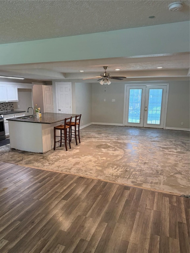 712 S Blackwell St, La Porte, TX 77571 - kitchen featuring wood finished floors, dark countertops, baseboards, a breakfast bar, and white cabinetry