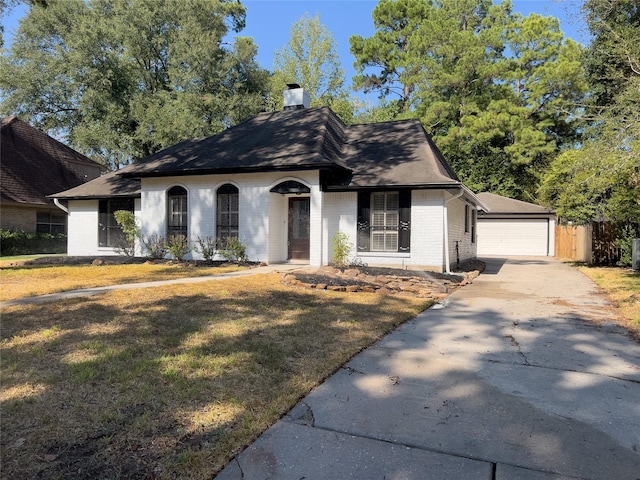 view of front of home with an outbuilding, a chimney, a front lawn, a detached garage, and brick siding