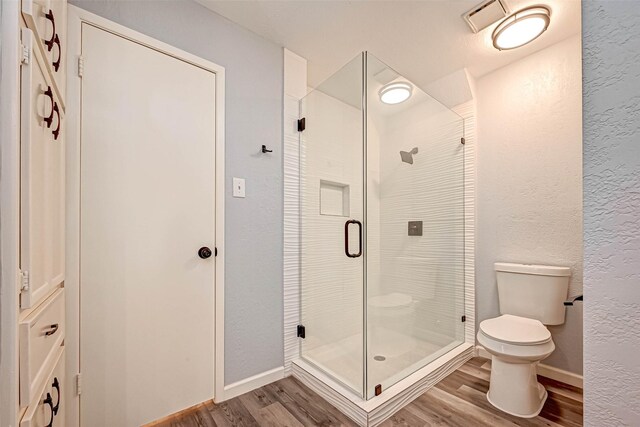 bathroom with hardwood / wood-style floors, toilet, and walk in shower