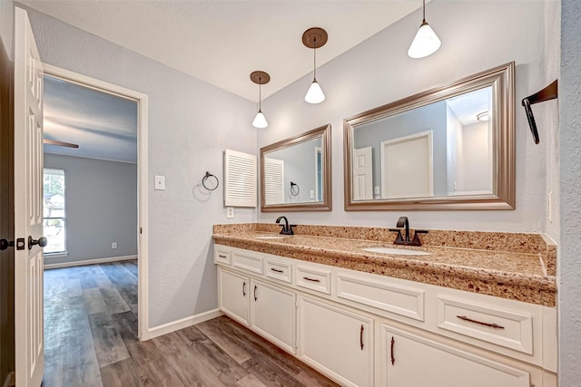 bathroom featuring double vanity, wood finished floors, baseboards, and a sink