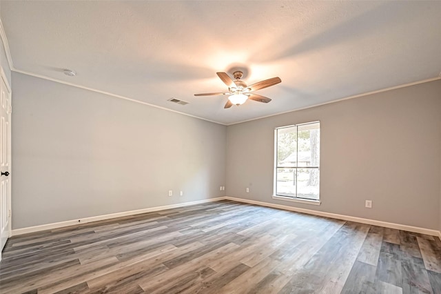 empty room featuring visible vents, ornamental molding, a ceiling fan, wood finished floors, and baseboards