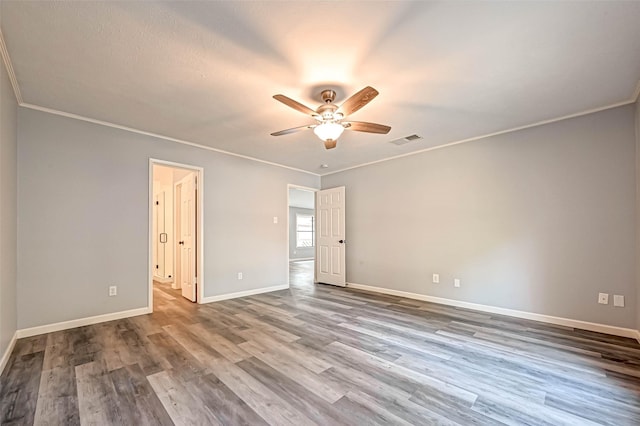 unfurnished bedroom with visible vents, crown molding, baseboards, and wood finished floors