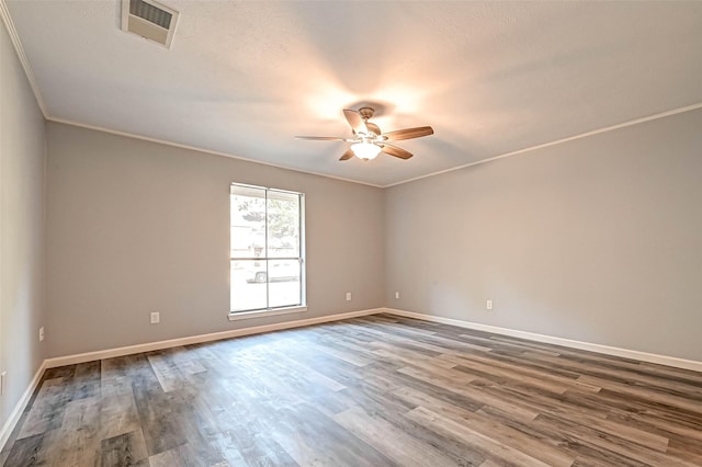 spare room featuring wood finished floors, baseboards, visible vents, ceiling fan, and crown molding