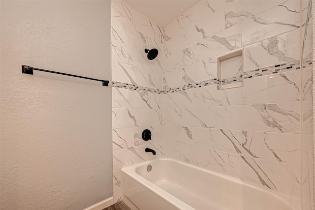 full bath with baseboards, shower / tub combination, and a textured wall