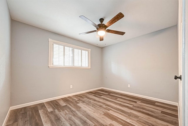 spare room with baseboards, wood finished floors, and ceiling fan