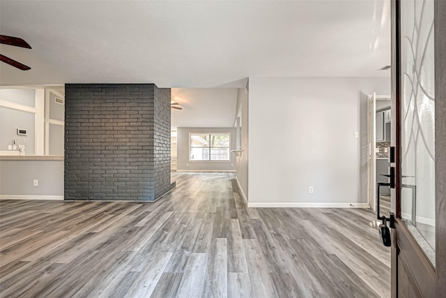 unfurnished living room featuring a sink, baseboards, a ceiling fan, and wood finished floors