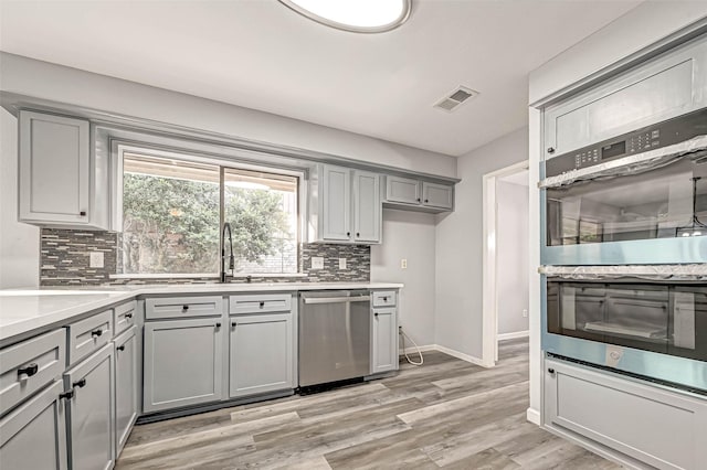 kitchen featuring visible vents, gray cabinetry, appliances with stainless steel finishes, light wood finished floors, and light countertops