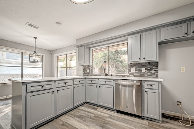 kitchen featuring dishwasher, light wood-type flooring, tasteful backsplash, and hanging light fixtures