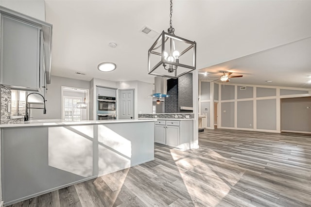 kitchen featuring vaulted ceiling, sink, hardwood / wood-style floors, gray cabinets, and hanging light fixtures