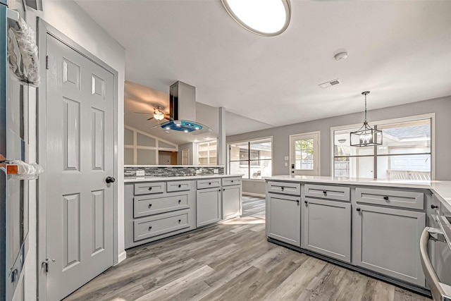 kitchen with a wealth of natural light, visible vents, gray cabinets, and island range hood