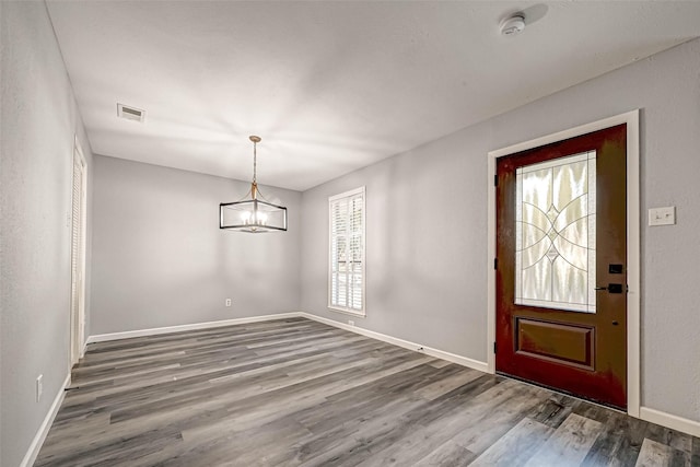 entryway featuring visible vents, baseboards, an inviting chandelier, and wood finished floors