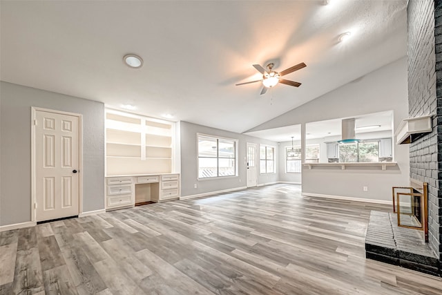 unfurnished living room featuring ceiling fan, plenty of natural light, light wood-type flooring, and a brick fireplace