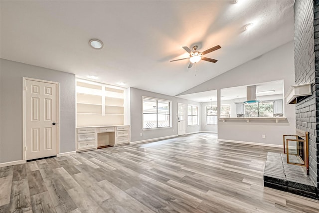 unfurnished living room with wood finished floors, a fireplace, built in desk, and ceiling fan