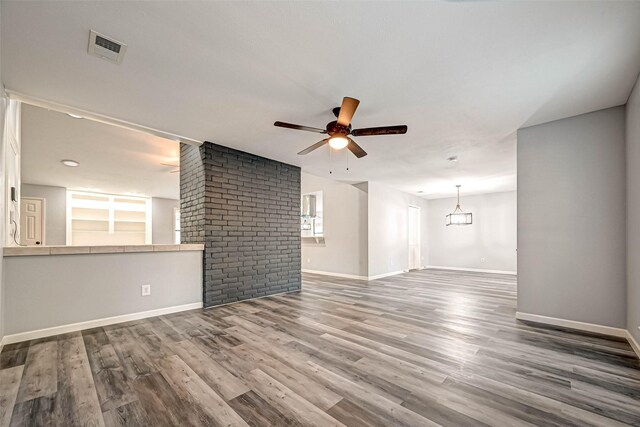 unfurnished living room featuring ceiling fan with notable chandelier and wood-type flooring