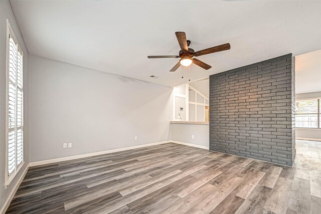 empty room featuring hardwood / wood-style flooring, ceiling fan, and brick wall