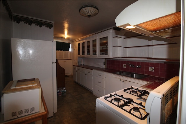 kitchen featuring sink, white refrigerator, dark tile patterned floors, tasteful backsplash, and white cabinets