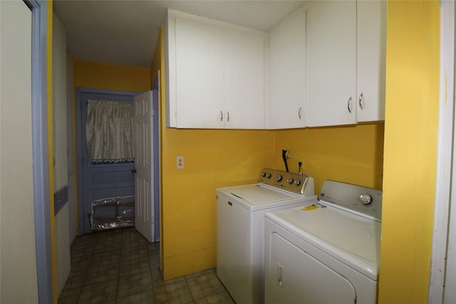 washroom featuring washer and dryer, dark tile patterned flooring, and cabinets