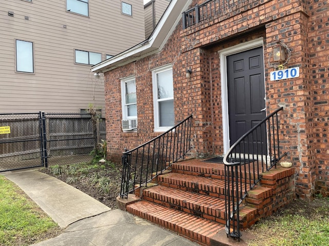 view of exterior entry featuring brick siding, fence, and a gate