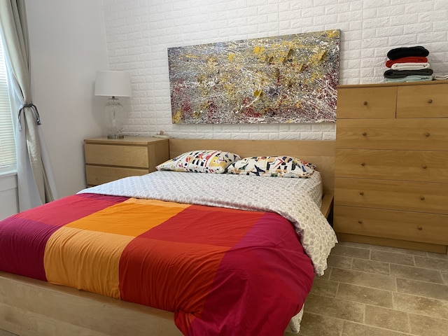 bedroom with brick wall and tile patterned flooring