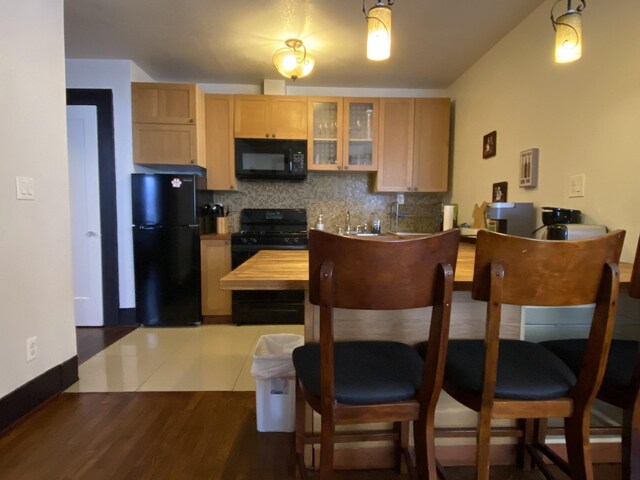 kitchen with light brown cabinets, decorative backsplash, hardwood / wood-style floors, sink, and black appliances