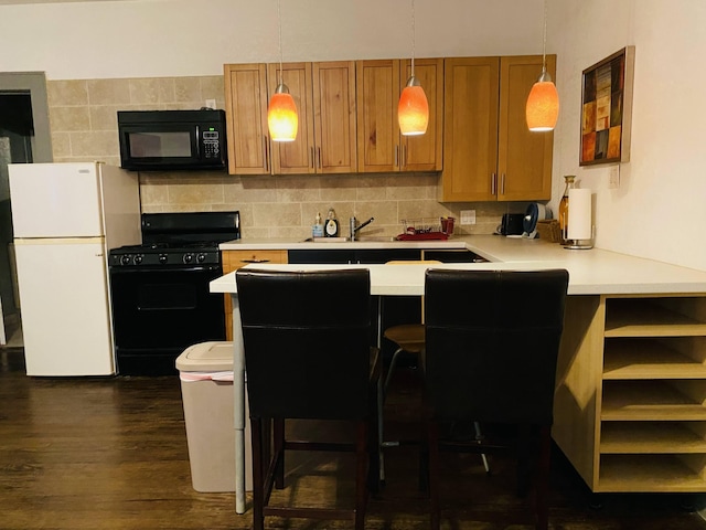 kitchen with backsplash, a kitchen bar, decorative light fixtures, dark wood-type flooring, and black appliances