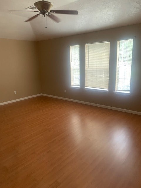 spare room featuring ceiling fan, hardwood / wood-style floors, and a healthy amount of sunlight