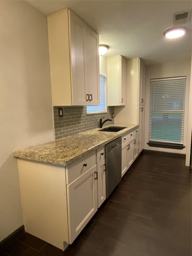 kitchen with light stone countertops, white cabinetry, sink, and dishwasher