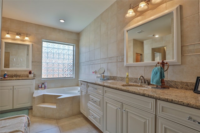 bathroom featuring tile walls, tile patterned floors, tiled tub, and vanity