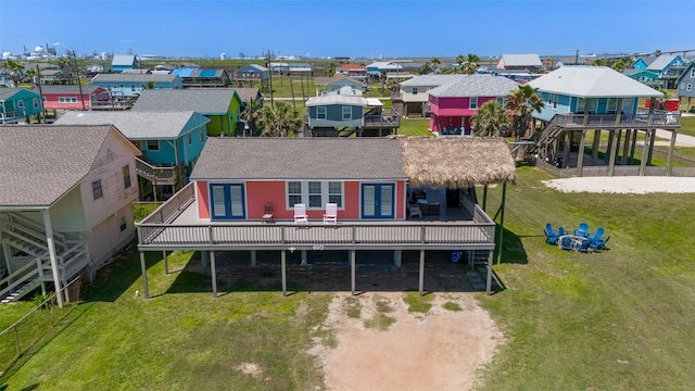 610 Surf Dr, Surfside Beach, TX 77541 - back of house with a lawn, a wooden deck, a shingled roof, and a residential view