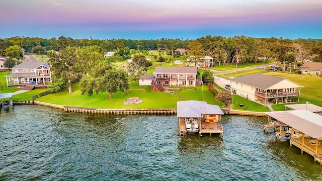 aerial view at dusk featuring a water view and a residential view