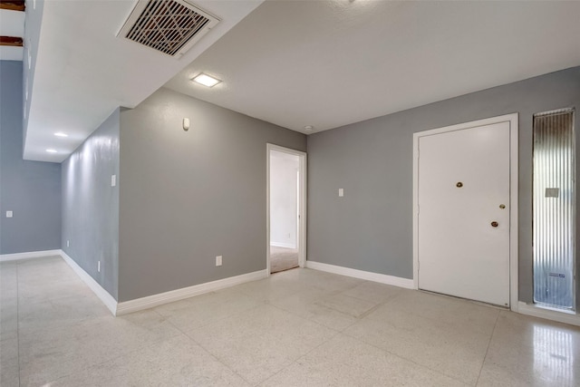 interior space featuring light speckled floor, visible vents, and baseboards