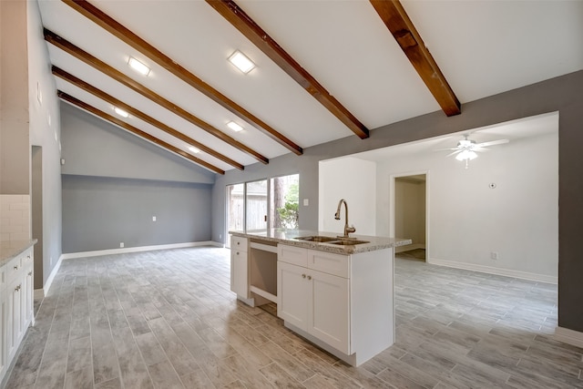 kitchen with white cabinetry, sink, a center island with sink, beamed ceiling, and ceiling fan