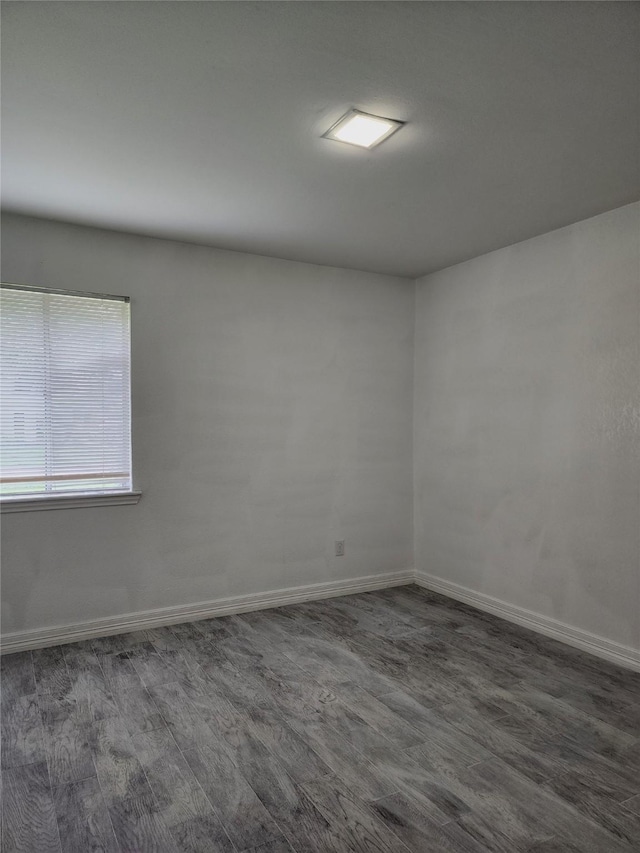 empty room with dark wood-style flooring and baseboards