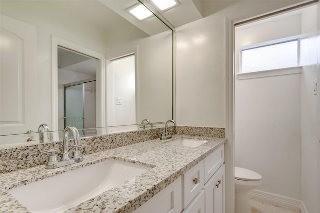 full bathroom with a stall shower, a sink, toilet, and double vanity