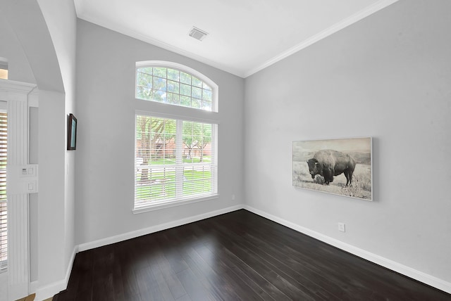 unfurnished room featuring a wealth of natural light, vaulted ceiling, ornamental molding, and dark hardwood / wood-style floors