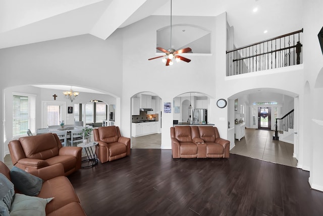 tiled living room featuring ceiling fan with notable chandelier, high vaulted ceiling, and a healthy amount of sunlight