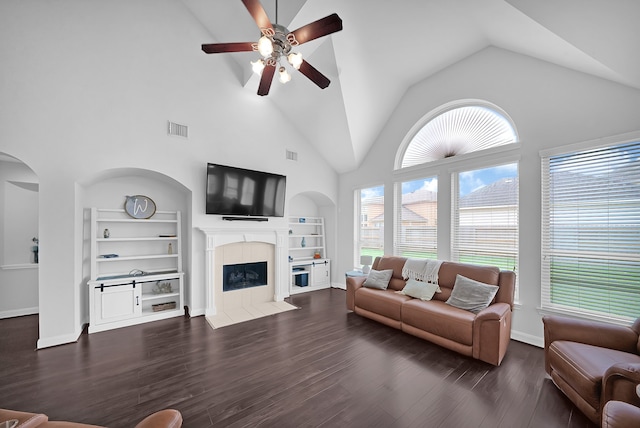 living room featuring ceiling fan, a tile fireplace, dark hardwood / wood-style flooring, and built in shelves